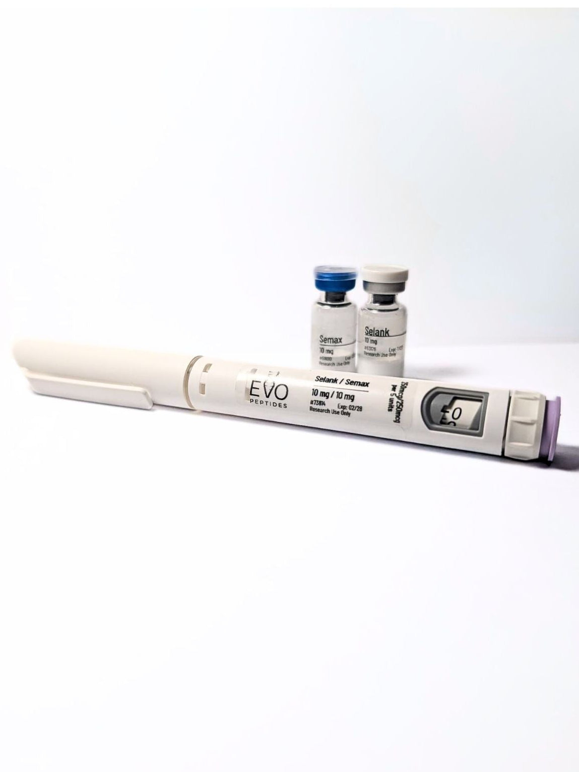 A white and gray semax and selank injector pen shown horizontally, with two small vials of rapid-acting insulin standing behind it on a plain white background.